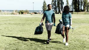 Two people walking through a grassy feild.