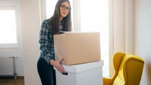 A picture of a student in a house holding boxes.