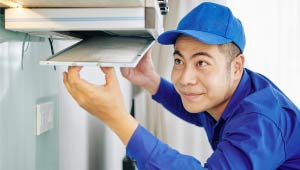 A professional person cleaning a kitchen hood.
