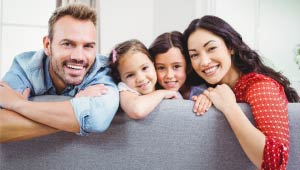 Two parents and two children on a couch smiling at the camera.