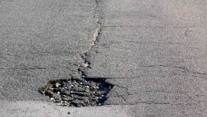 A picture of a street with a pothole.